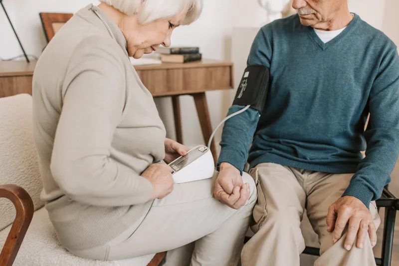 An older couple taking a blood pressure reading together at home