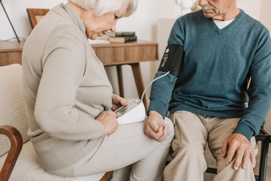 An older couple taking a blood pressure reading together at home