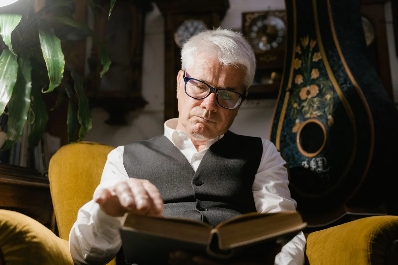 An older man reading in his own armchair at home