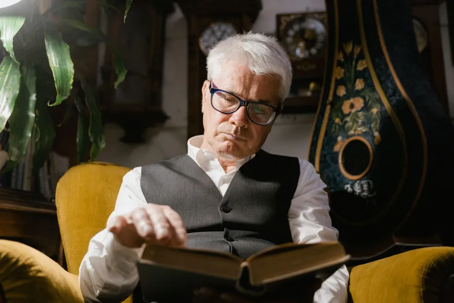 An older man reading in his own armchair at home