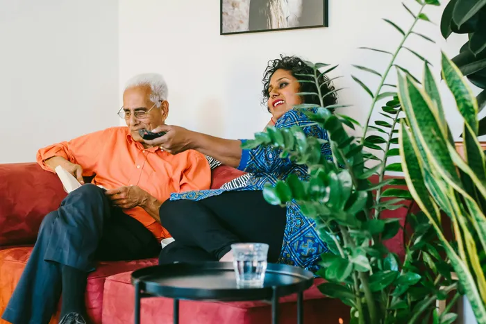 An older man at home, talking with a family member on the sofa