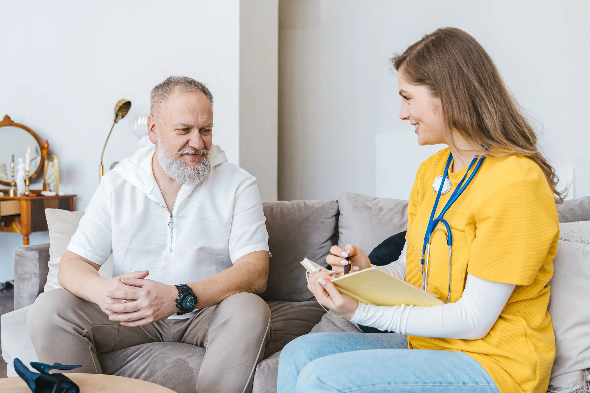 A community nurse talking with an older man in the lounge room of his own home