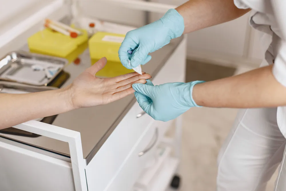 A nurse in gloves applying a fresh dressing to a client's hand